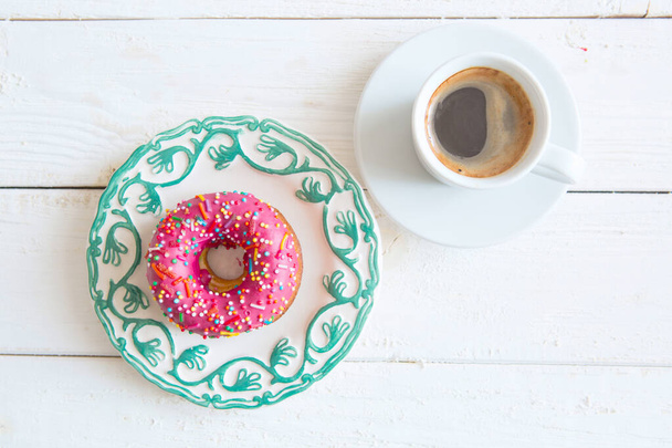 Pink donut and coffee on wood background. - Valokuva, kuva