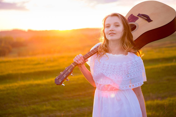portrait of the beautiful young woman  with guitar in the field - Foto, immagini