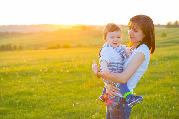 Mother and lovely son at sunny field with intentional sun glare. Happy family concept. - Foto, imagen