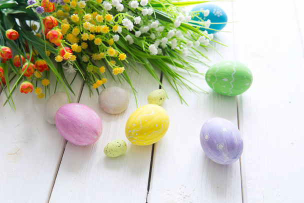 Colorful easter eggs and flowers on wooden table. - Foto, Imagem
