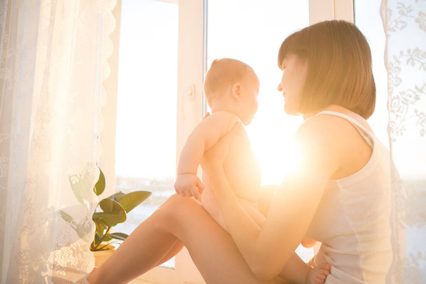 Soft comfort photo young mother with baby at home in white room near window - Foto, Bild