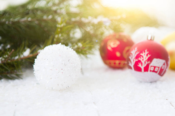 Red and white xmas holiday balls ornament sits among pine or spruce branches on wooden table. - Fotoğraf, Görsel