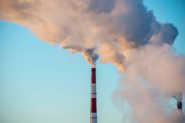 A poderosa chaminé industrial está fumando e emitindo dióxido de carbono para o meio ambiente. Conceito de poluição atmosférica e problema do aquecimento global - Foto, Imagem