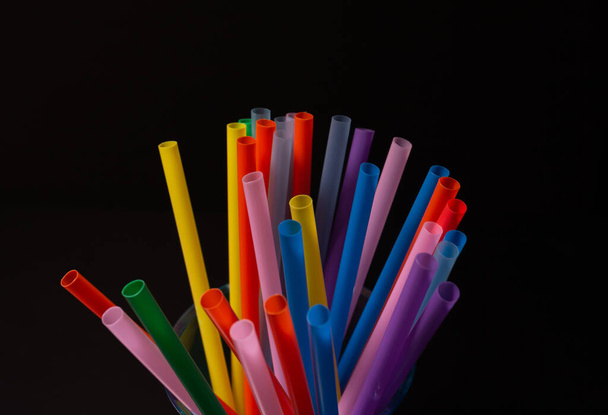 Vista de perto de palhas plásticas coloridas em um fundo preto. Textura. Conceito de proibição na UE. - Foto, Imagem