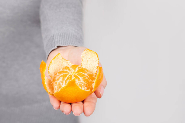 Hand with fresh tangerine on grey. - Foto, Imagem