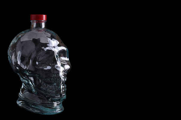 Siyah zemin üzerinde kafatası şeklinde boş cam şişe ve kopyalama alanı - Fotoğraf, Görsel