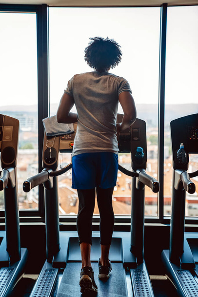 Счастливый здоровяк в спортзале делает упражнения на беговой дорожке - Фото, изображение