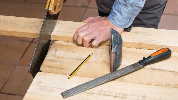 A carpenter in the process of renovating and making a wooden table - 写真・画像