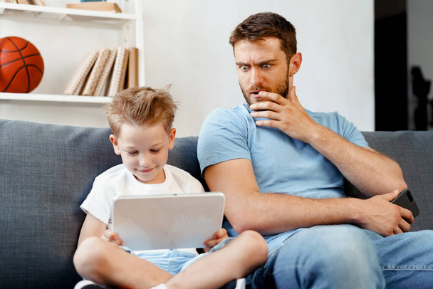 Worried father peeking at what his son is watching on digital tablet - Foto, Imagen