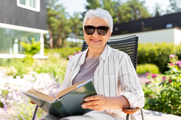 happy senior woman reading book at summer garden - Φωτογραφία, εικόνα