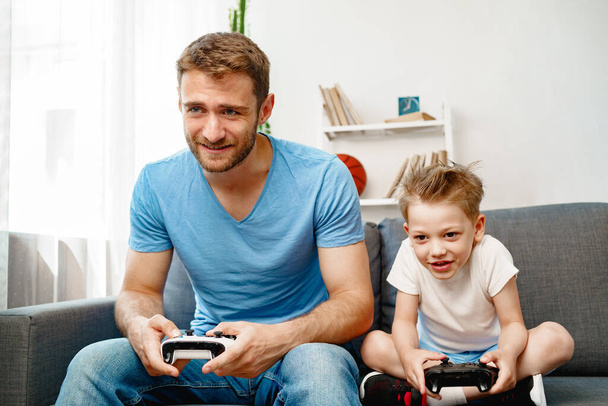 Father and his little son playing video games together at home - 写真・画像