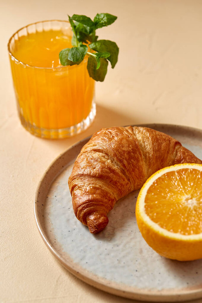 glass of orange juice and croissant on plate - Foto, Bild