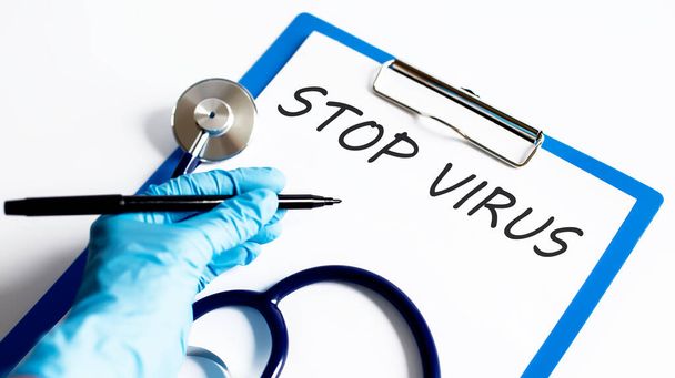 Paperi, jossa teksti Stop VIRUS pöydällä stetoskoopilla. Lääketieteellinen käsite - Valokuva, kuva