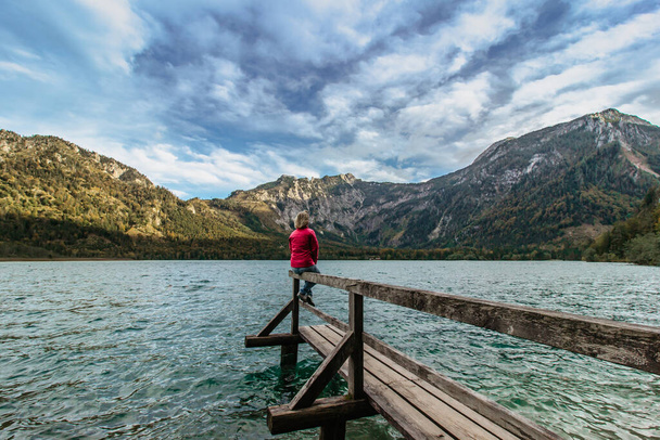 オーストリアの山の湖で休息中の少女。アルプスの景色を楽しむ女性旅行者。欲望の自由旅行の概念。夏休みの冒険シーン。休日にリラックスした女を. - 写真・画像