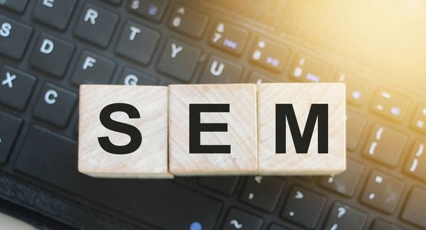SEM Search Engine Marketing γραμμένο σε ξύλινους κύβους στο πληκτρολόγιο του υπολογιστή. Βελτιστοποίηση σε απευθείας σύνδεση έννοια της επιχειρηματικής τεχνολογίας - Φωτογραφία, εικόνα
