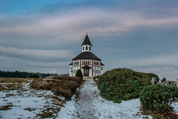 Piccola cappella Tesarovska rurale bianca con cimitero nel villaggio di Korenov, montagne Jizera, Repubblica Ceca. Veduta del paesaggio invernale al tramonto.Chiesa storica in legno. Paesaggio religioso. - Foto, immagini