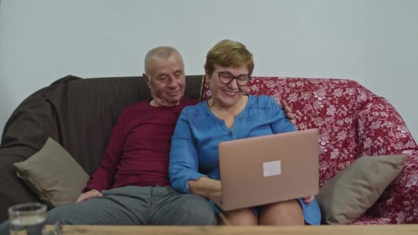 Egy idős nő videokommunikációról és mosolygásról beszél. Egy férfi ül a közelben és kémkedik.. - Felvétel, videó