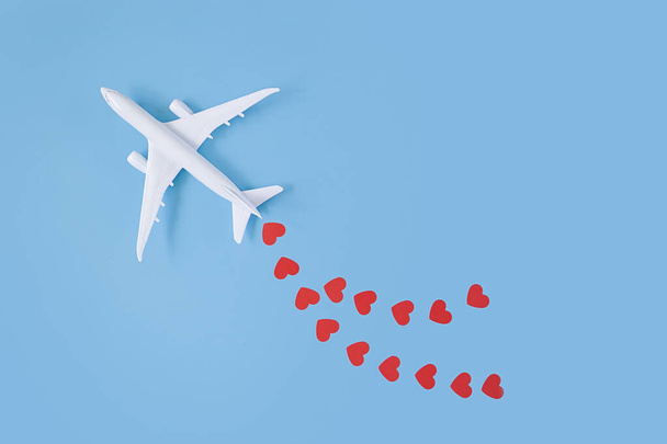 Happy Valentine's Day. Traveling as gift. model airplane on blue background with red hearts - Foto, immagini