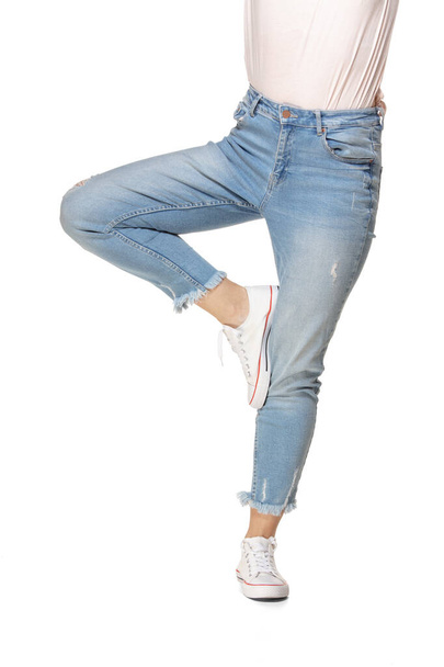 Beautiful female legs in blue jeans and sport shoes isolated on white background - Photo, image