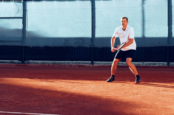 Young man plays tennis outdoors on tennis court in the morning - Φωτογραφία, εικόνα