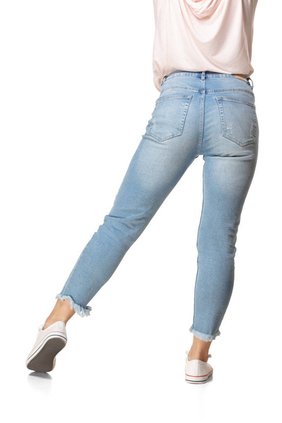 Widok z tyłu żeńskich nóg w niebieskich dżinsach i obuwiu izolowane na białym tle - Zdjęcie, obraz
