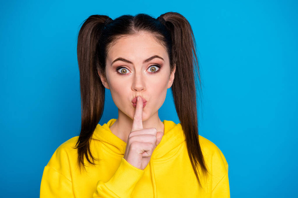 Closeup photo of pretty lady funny two tails hairdo hold finger on lips mouth keep silence know secret gossip wear casual yellow sweatshirt pullover isolated bright blue color background - Фото, зображення