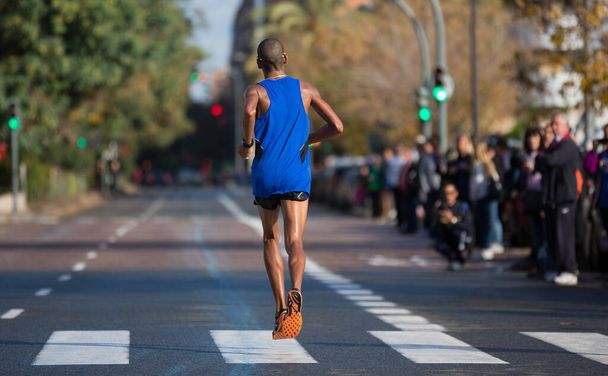 Марафонский бегун с видом сзади, пролетающий над дорогой - Фото, изображение