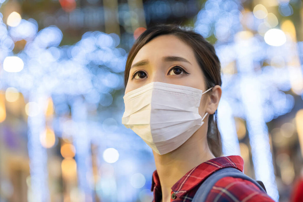 close up of asian young female backpacker wearing face mask in the Taipei city at night during quarantine coronavirus COVID-19 pandemic - Fotó, kép