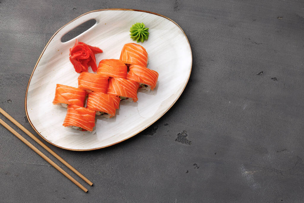 Top view of Philadelphia sushi roll on plate on black table - Zdjęcie, obraz