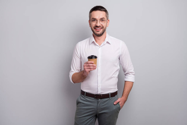 Portrait of his he nice attractive cheerful content classy successful mature man holding in hands enjoying drinking sweet latte isolated over light gray pastel color background - Photo, Image