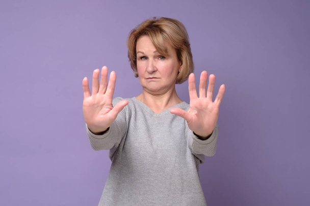Donna di mezza età che fa smettere di cantare con il palmo della mano seminando dieci dita. - Foto, immagini