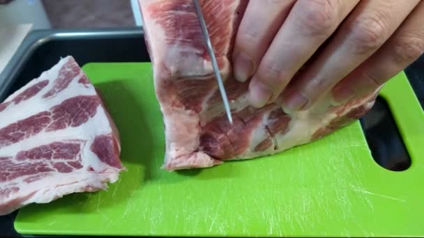 Una donna taglia un grosso pezzo di carne di maiale con un coltello. Carne con strati di grasso, collo di maiale. - Filmati, video