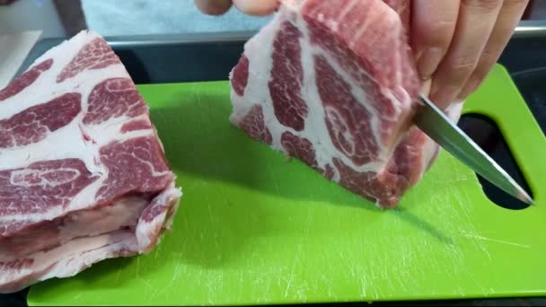 Una mujer corta un trozo grande de carne de cerdo con un cuchillo. Carne con capas de grasa, cuello de cerdo. 4k - Metraje, vídeo