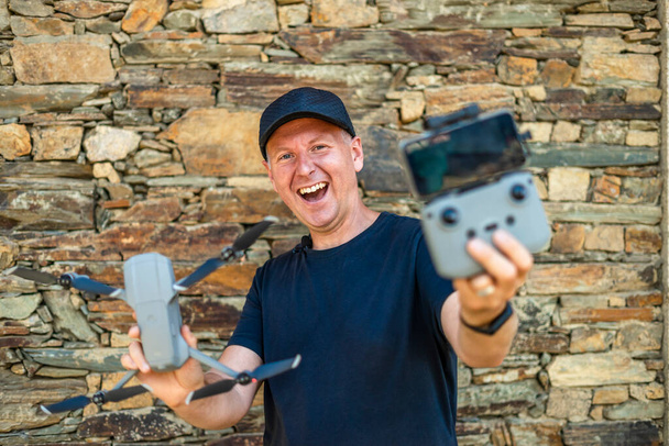 Emocionado hombre sosteniendo su nuevo dron con control remoto y teléfono listo para fl - Foto, imagen