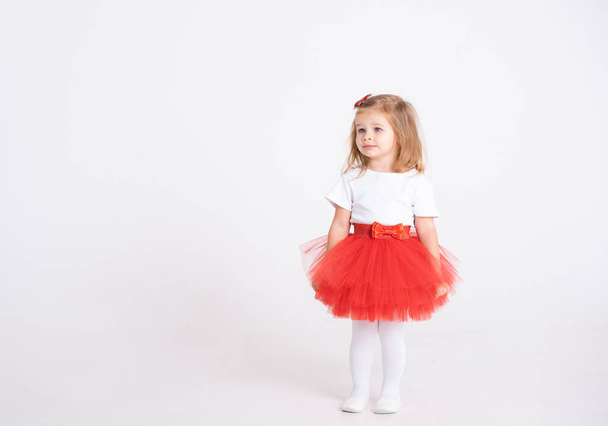 白い背景に赤いスカートと白いTシャツの幼児の女の子。バレンタインデーのコンセプト - 写真・画像
