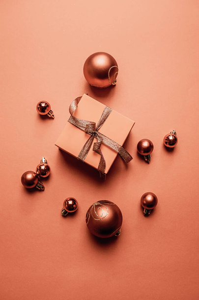 Creatieve winter achtergrond met geschenken, verpakt in bruin papier met lint strik en xmas bruine ballen op oranje achtergrond. Vrolijk Kerstfeest en Gelukkig Nieuwjaar. - Foto, afbeelding