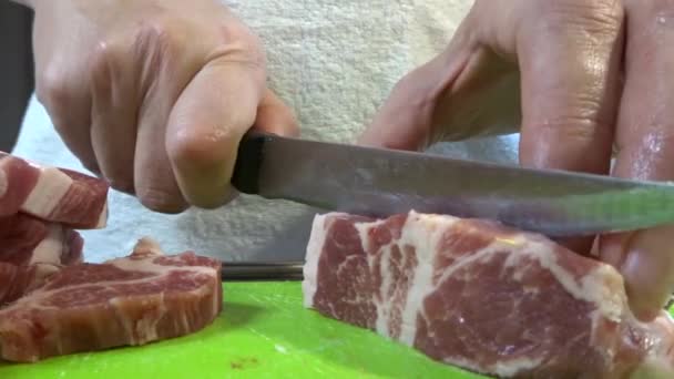 Une femme coupe un gros morceau de viande de porc avec un couteau. Viande avec couches de graisse, cou de porc. - Séquence, vidéo