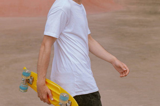Détail d'un jeune homme posant avec une planche à roulettes - Photo, image