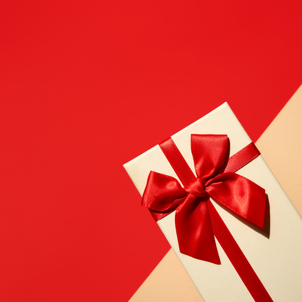 Cadeau blanc avec ruban rouge sur le fond rouge vif - Photo, image