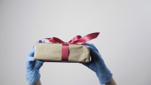 mãos em luvas de proteção azul dar caixa de presente com fita. COVID-19 Natal - Filmagem, Vídeo