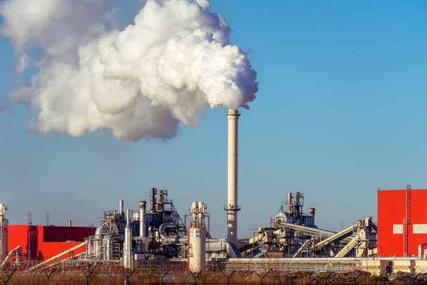 Trubky s obrovskými mraky kouře v továrně zblízka proti modré obloze za slunečného dne. Pojem ekologie, znečištění životního prostředí - Fotografie, Obrázek