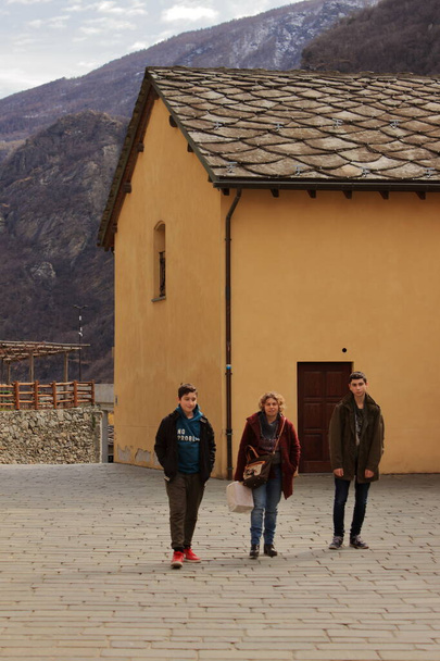 moeder met twee kinderen loopt langs een stenen weg tijdens een bezoek aan een dorp in de Italiaanse Alpen - Foto, afbeelding
