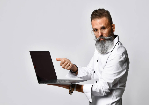 Stylish bearded hipster man in eyewear pointing to laptop - Фото, зображення