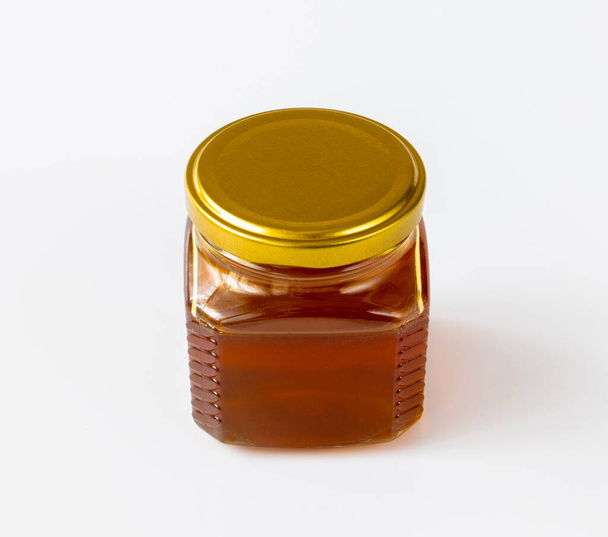 Honey in the glass jar on a light background - Fotografie, Obrázek
