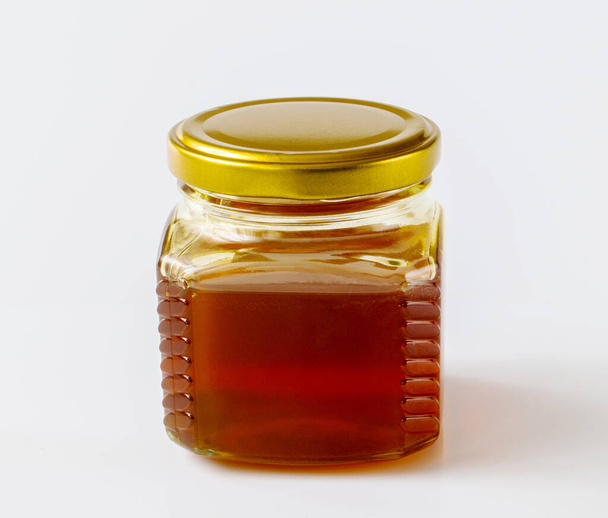 Honey in the glass jar on a light background - Fotografie, Obrázek