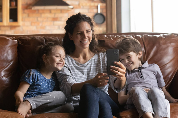 Millennial mother and two children enjoying family rest using phone - Fotó, kép