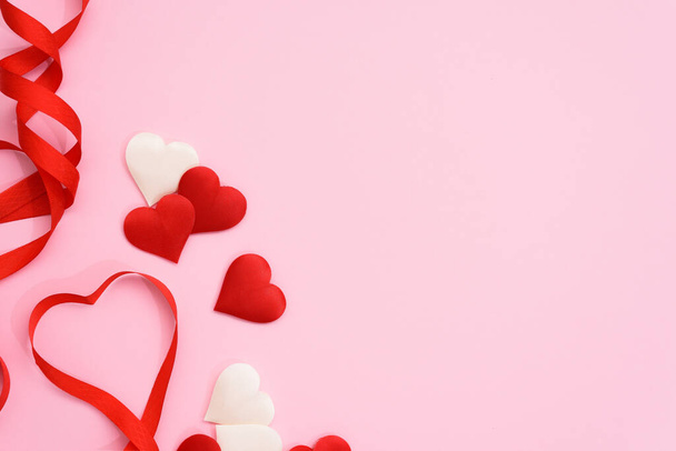 Valentýna červená stuha křivky ve tvaru srdce na růžovém pozadí. slavnostní zázemí pro svatební a blahopřání, mokup, kopírovací prostor. - Fotografie, Obrázek