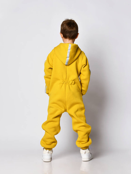 Boy in yellow sportswear back view studio shot - Фото, зображення