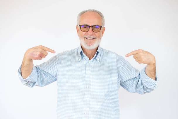 Vanhempi komea mies päällään rento paita ja lasit yli eristetty valkoinen tausta näyttää luottavainen hymyillen kasvot, osoittaa itseään sormilla ylpeä ja onnellinen. - Valokuva, kuva