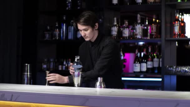 Mladý nováček barman stážista připravuje koktejl neopatrný chlap míchá nápoj a led v třepačce - Záběry, video